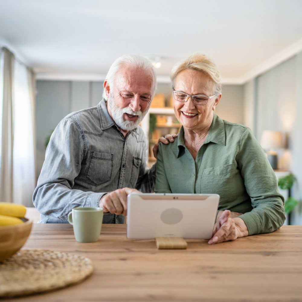Senior couple caucasian old man and woman husband and wife pensioner grandfather and grandmother use digital tablet for online video call at home in bright room real people family concept copy space